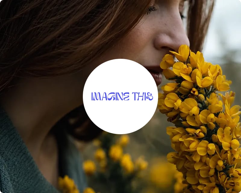 A woman smelling a bunch of yellow flowers in a natural outdoor setting, with the Imagine This logo overlaid in the centre