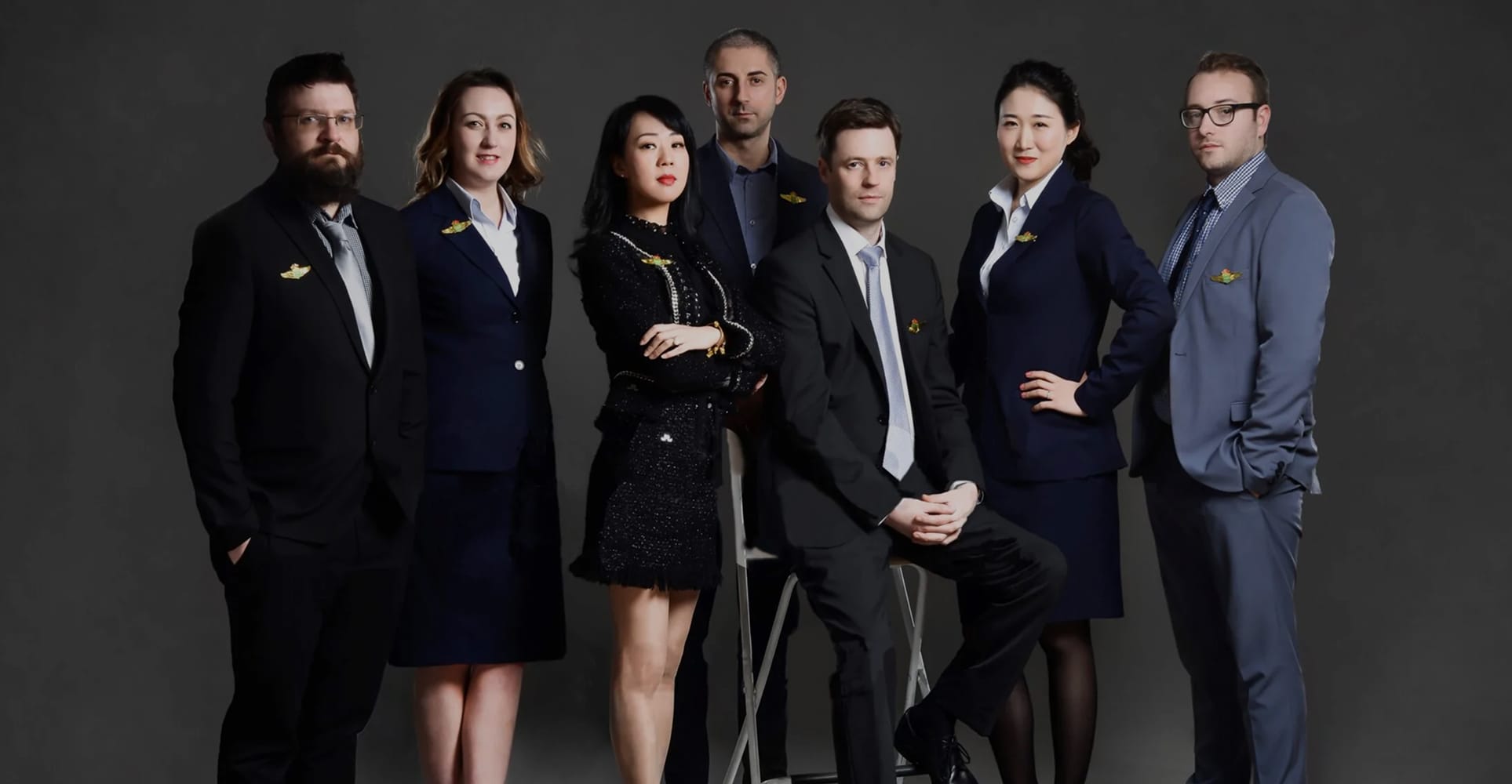 Seven J&P Accountants team members posed together in professional business attire against a dark studio background, with the J&P Accountants logo displayed to the right