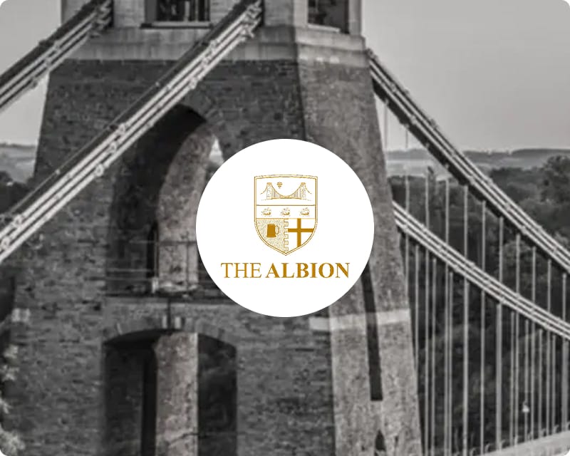 The Albion Bristol crest logo overlaid on a black and white close-up photograph of the Clifton Suspension Bridge tower in Bristol